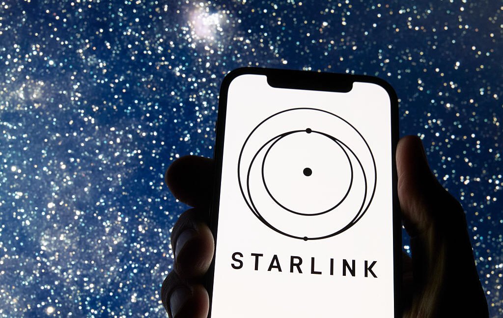 starlink logo displayed on smartphone with starry sky background